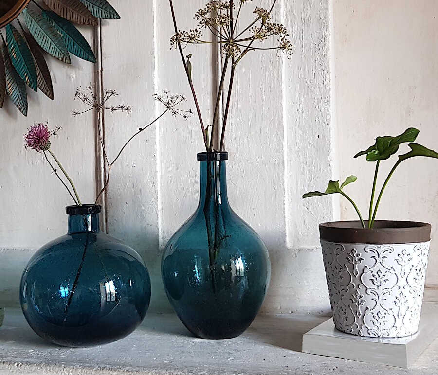 Composition avec vases bouteilles bleus et cache-pot blanc gravé de chez Deco-Delight.