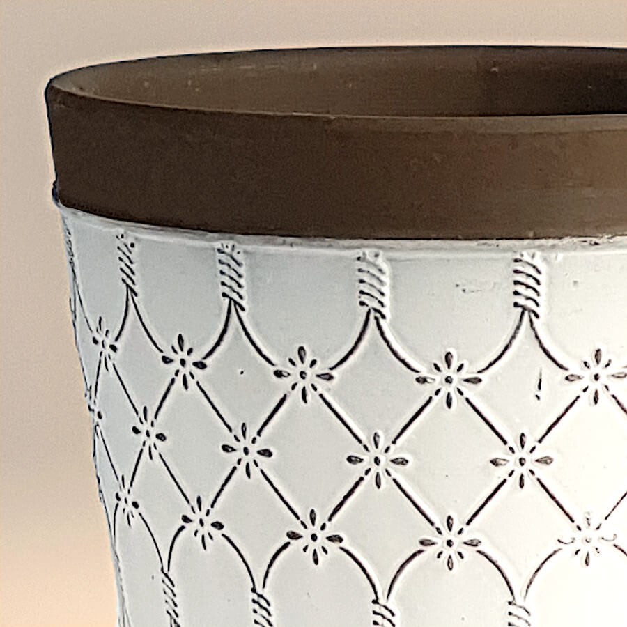 Détail de la gravure en losanges entrelacés sur céramique blanche.