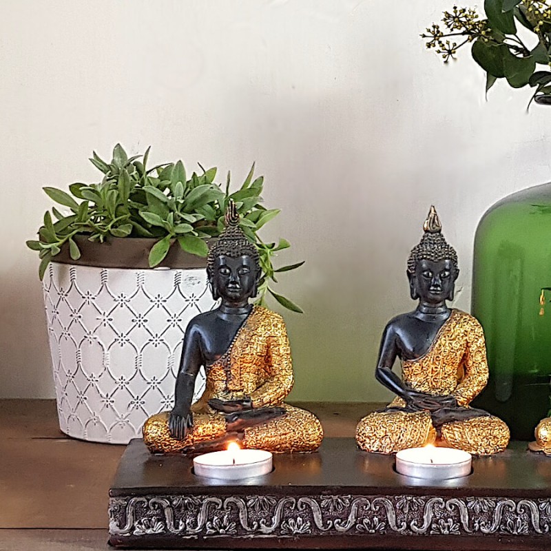 Cache-pot blanc et marron entouré de statues de Bouddha dorées de chez Deco-Delight.