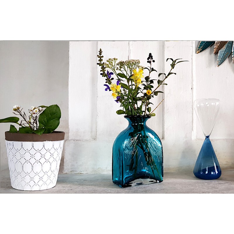 Cache-pot croisillons sur console près d'un vase-flacon bleu et d'un sablier Deco-Delight.