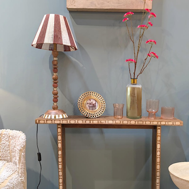 Mise en scène du vase irisé sur une console avec fleurs rouges.