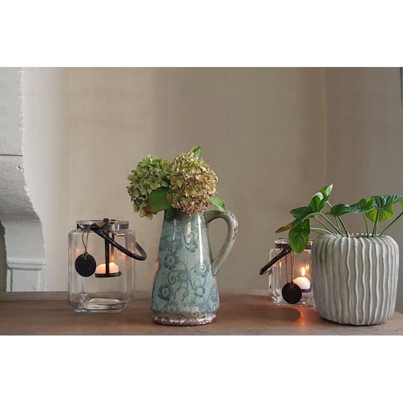 Composition déco incluant le pichet, des lanternes et une plante en cache-pot.