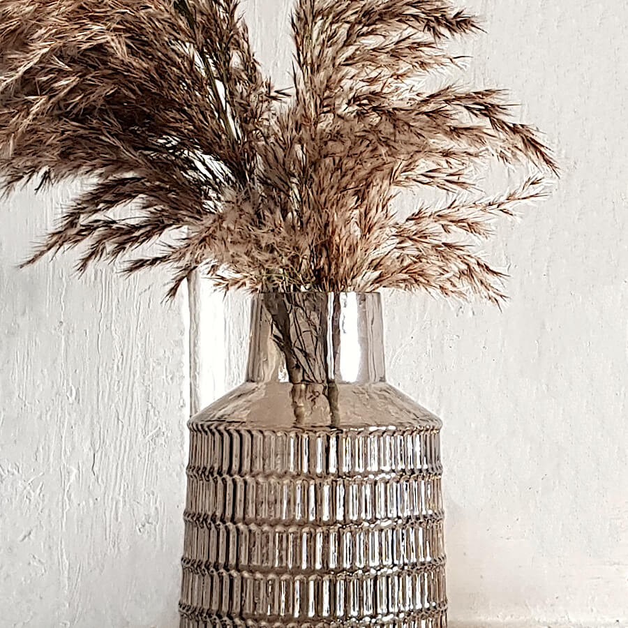 Focus sur le goulot resserré et la texture géométrique du verre.