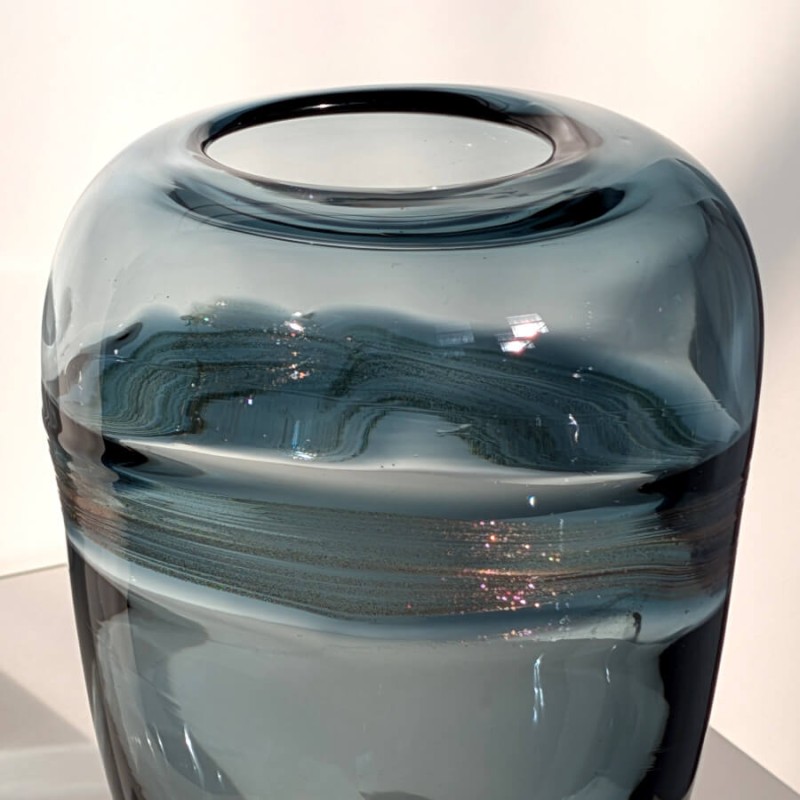 Focus sur la transparence du verre bleu et l'ouverture du vase.