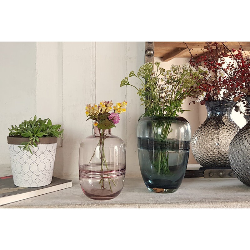 Le vase bleu-gris fleuri à côté du cache-pot blanc et marron, et d'autres vases Deco-Delight, sur une cheminée.