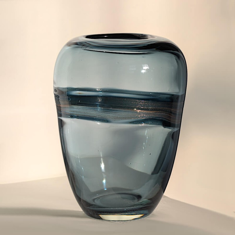 Vue de face soulignant la forme ovoïde et l'éclat de l'or de ce vase, posé dans un coin de la pièce.