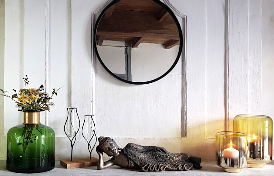 Scène décorative complète avec miroir, statuette et soliflore sur une étagère.