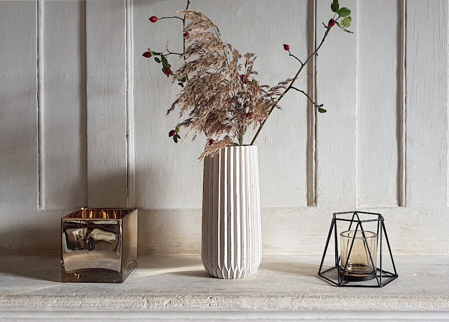 Le vase blanc-crème fleuri hauteur 25 cm sur une console aux côtés de photophores Deco-Delight.