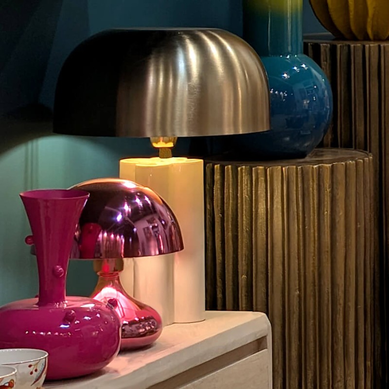 La lampe rose métallisé s'intègre dans une collection de luminaires et d'objets aux tons clairs ou vifs.