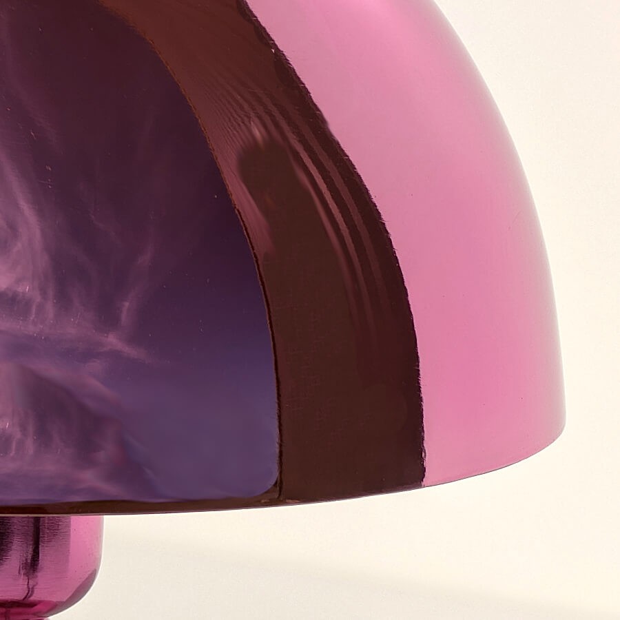 Très gros plan sur la coupole métallique rose révélant l'effet miroir et la brillance du fini.