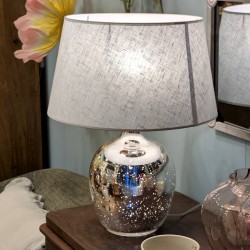 Mise en scène chaleureuse de la lampe allumée sur un chevet en bois foncé.