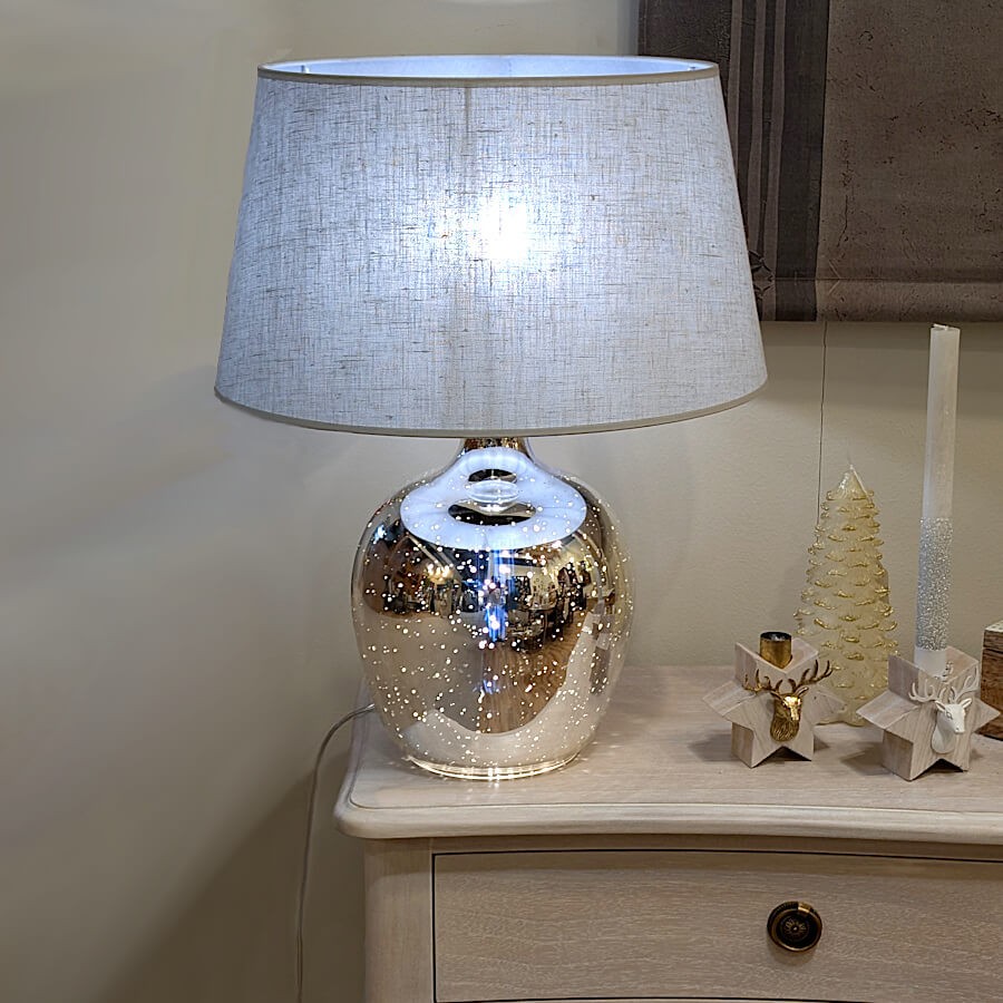 Vue de la lampe éclairant un coin de salon avec des reflets argentés diffus.