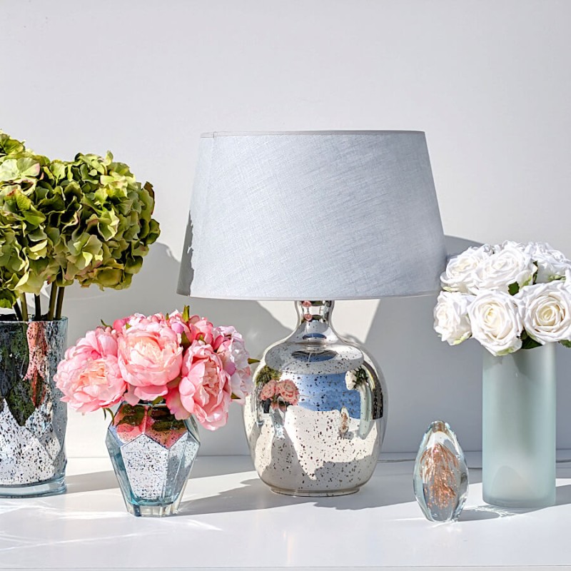 La lampe présentée dans un décor floral soulignant son aspect élégant et naturel.