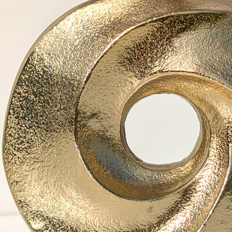 Zoom artistique sur la base en aluminium doré, mettant en lumière le fini martelé et la courbure élégante tourbillonnante.
