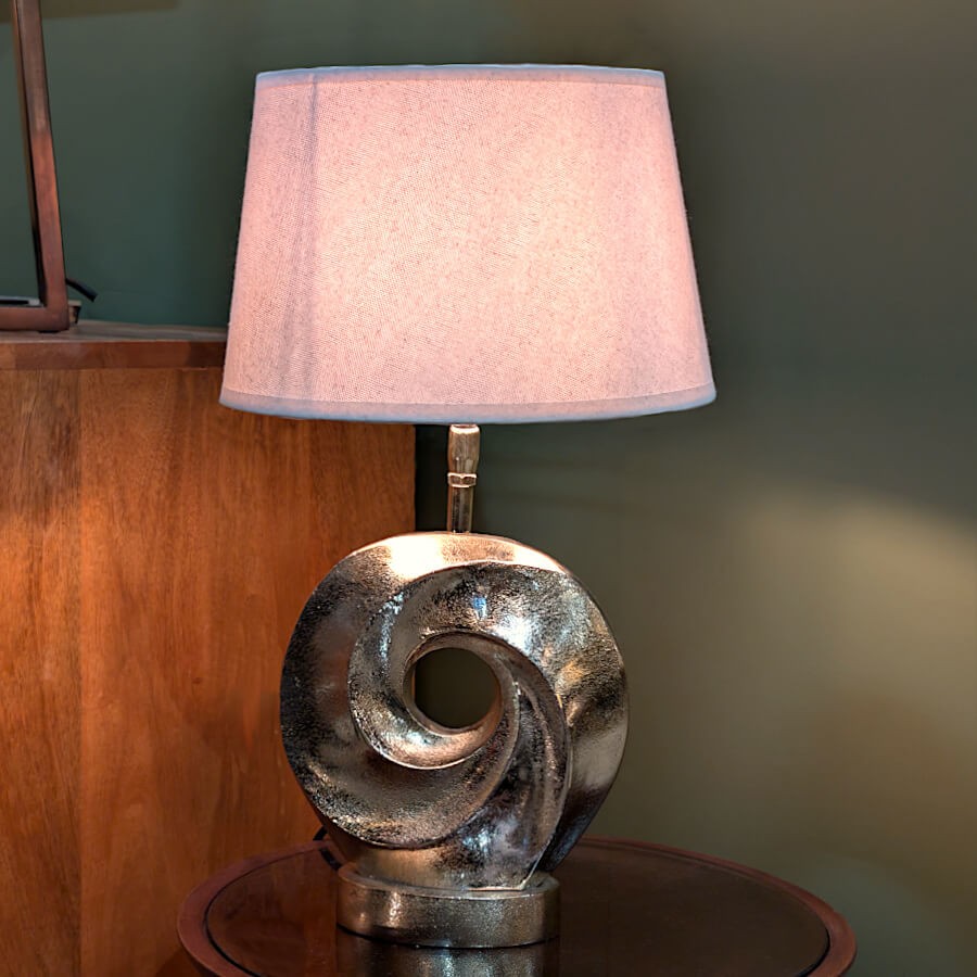 Vue d'ensemble de la lampe allumée dans un décor d'intérieur chaleureux sur fond de mur vert sombre.