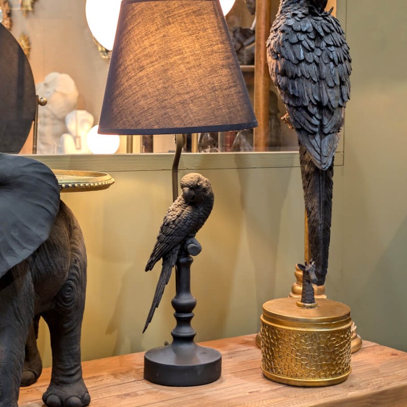 Lampe oiseau allumée sur un buffet bois, créant une lumière d'ambiance.