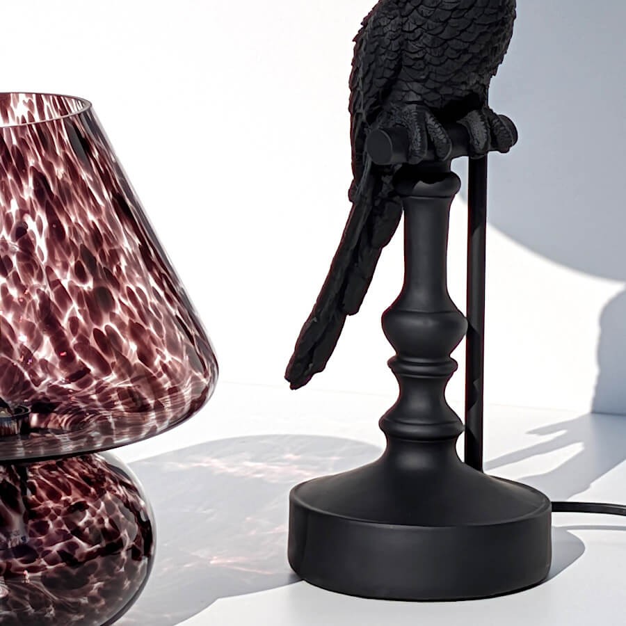 Zoom sur la base cylindrique et le bas du corps du perroquet.