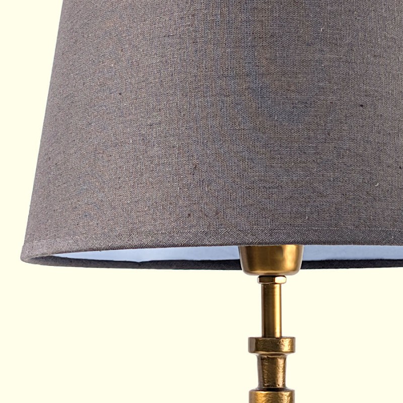 Détail de l'abat-jour en tissu gris foncé montrant la qualité du tissage et la fixation dorée.