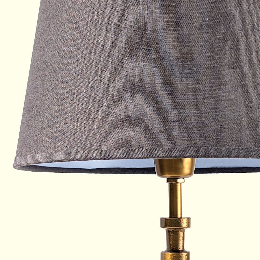 Détail de l'abat-jour en tissu gris foncé montrant la qualité du tissage et la fixation dorée.