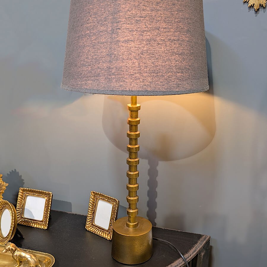 Gros plan de la lampe éclairée soulignant le contraste entre le métal brillant et l'abat-jour textile.