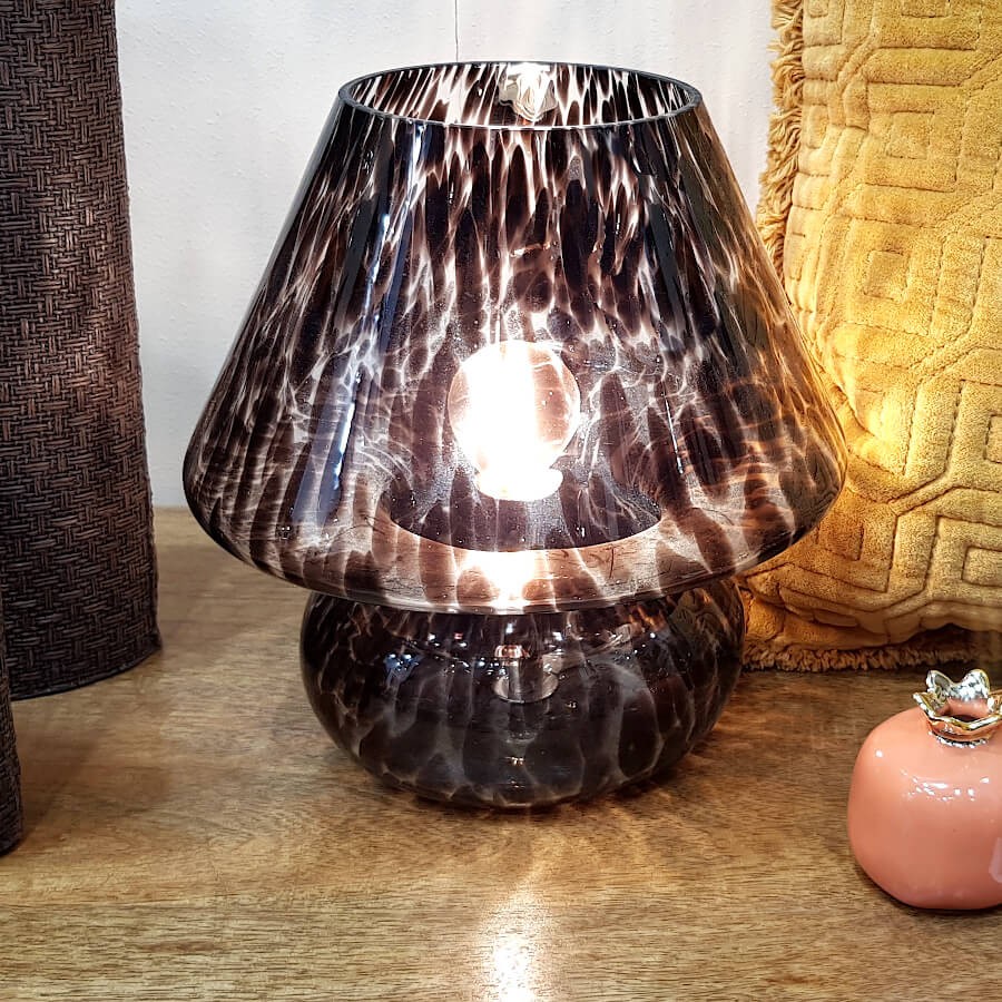 Vue rapprochée de la lampe allumée soulignant la transparence et le relief du verre.