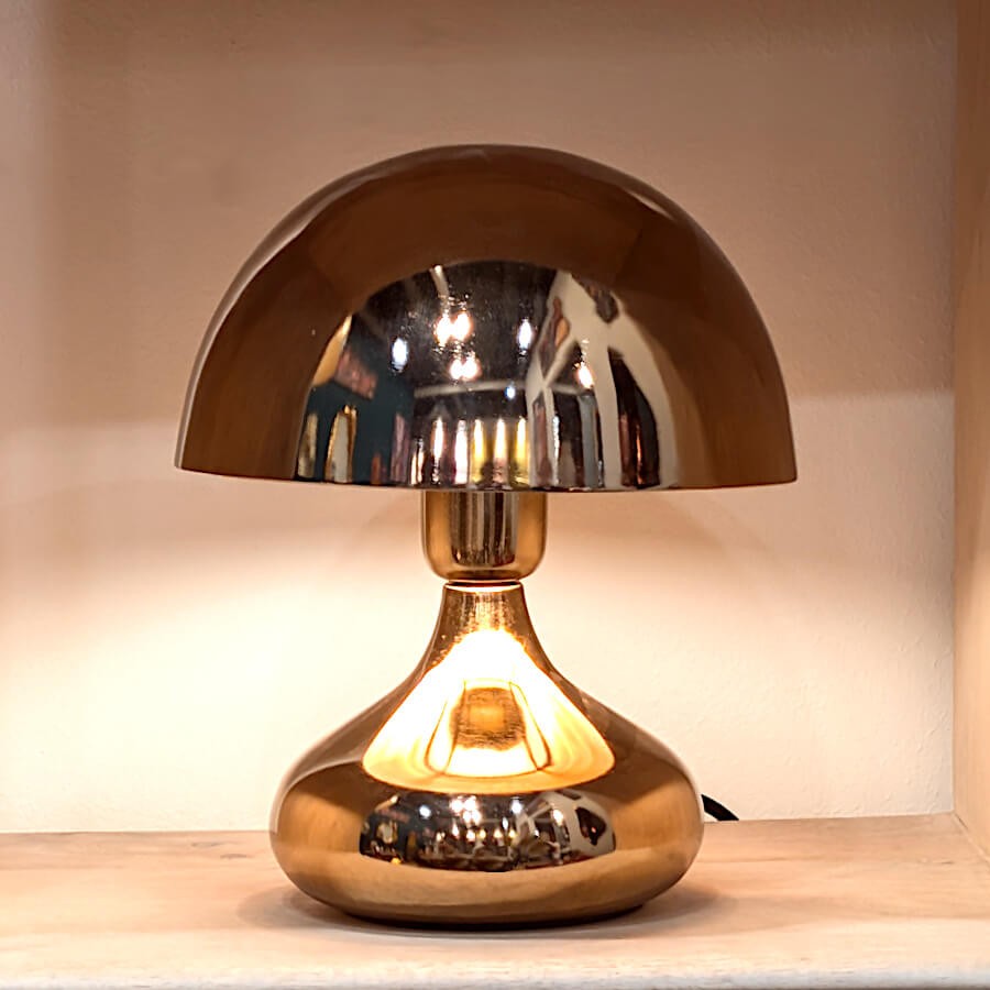 Lampe champignon cuivrée éclairée créant une ambiance chaleureuse et vintage.