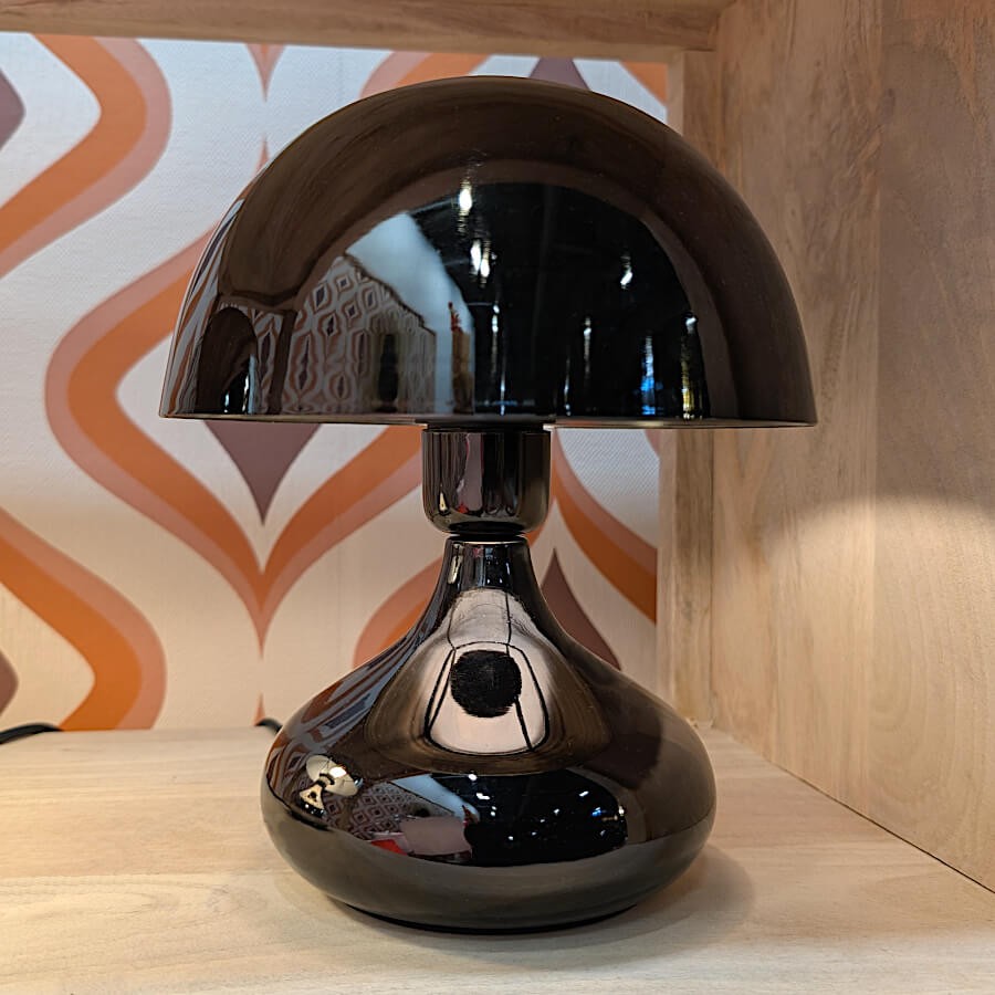 Mise en scène rétro-chic avec la lampe noire sur fond de papier peint graphique.