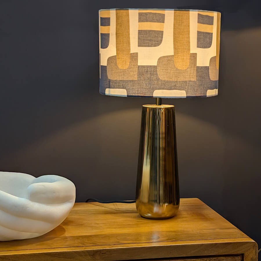 Mise en situation de la lampe graphique sur un meuble en bois, éclairage chaleureux de salon.