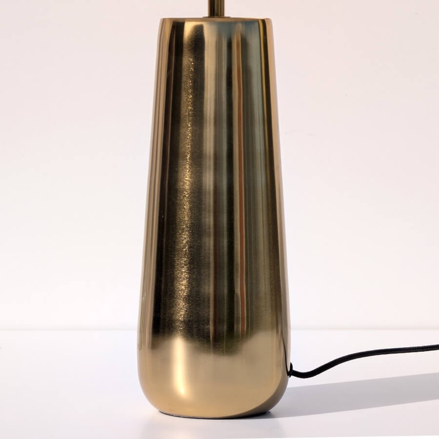 Gros plan sur le pied conique élancé en métal doré à la finition brossée élégante.