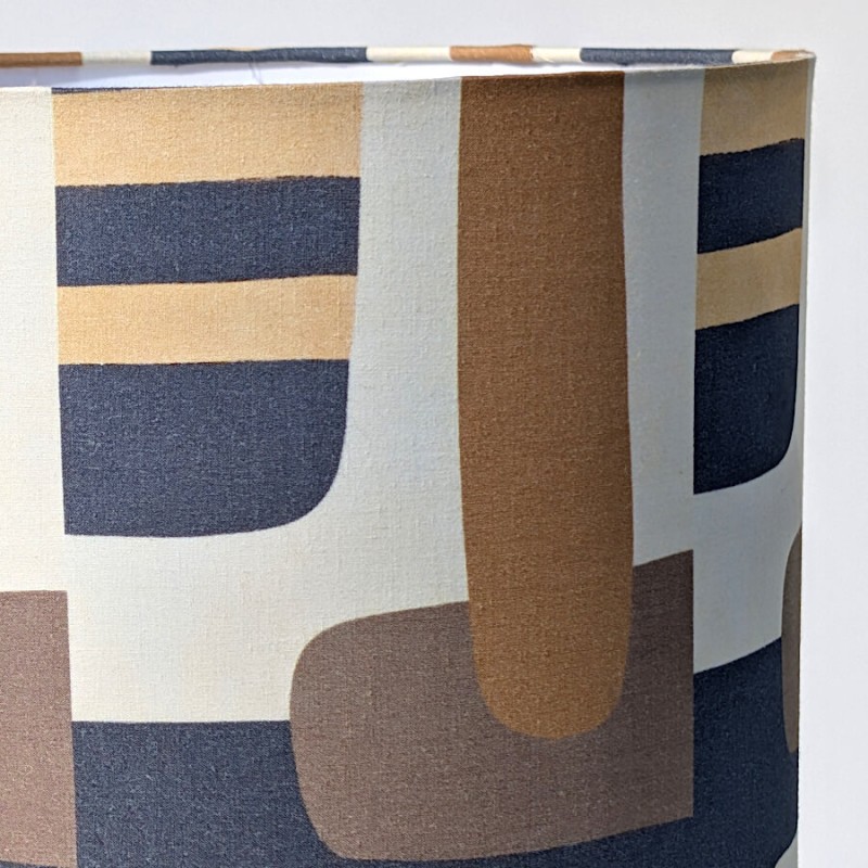 Zoom sur le motif géométrique de l'abat-jour rétro chic aux nuances ocre, bleu-gris et beige.