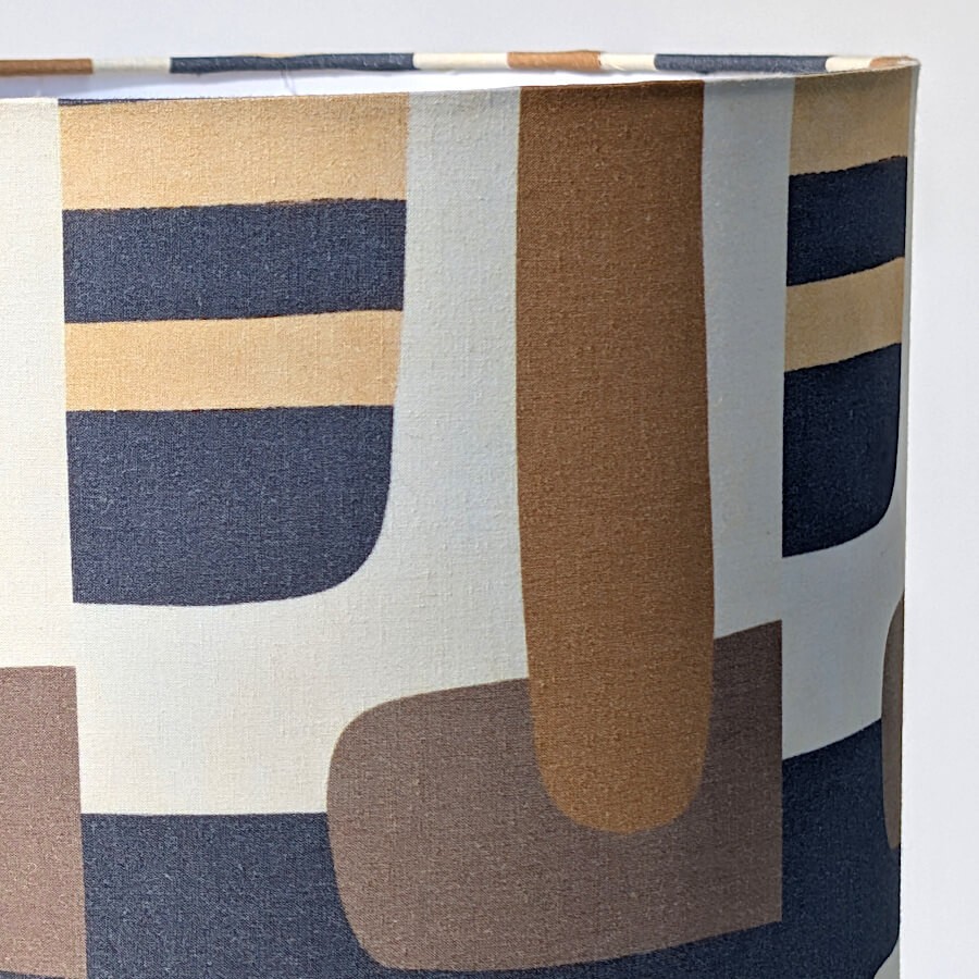 Zoom sur le motif géométrique de l'abat-jour rétro chic aux nuances ocre, bleu-gris et beige.