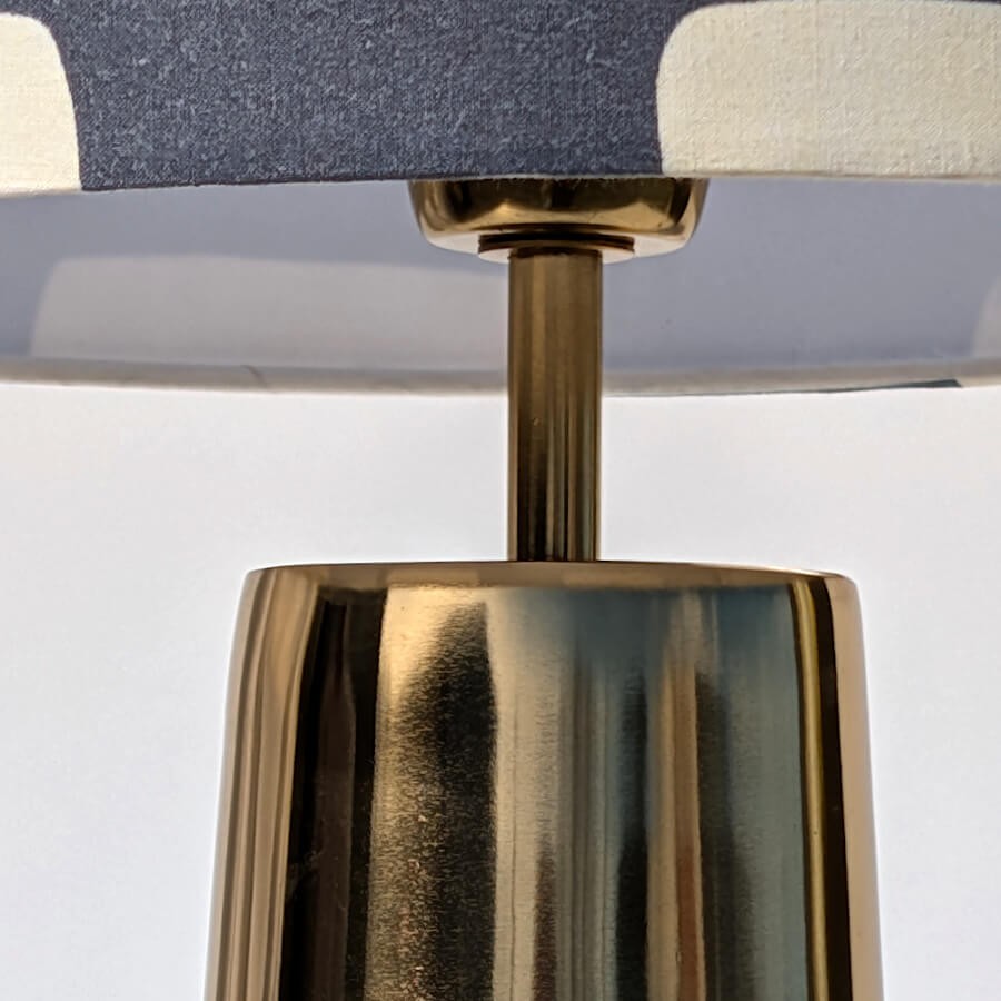 Détail de la tête de lampe et du support d'abat-jour en métal doré.