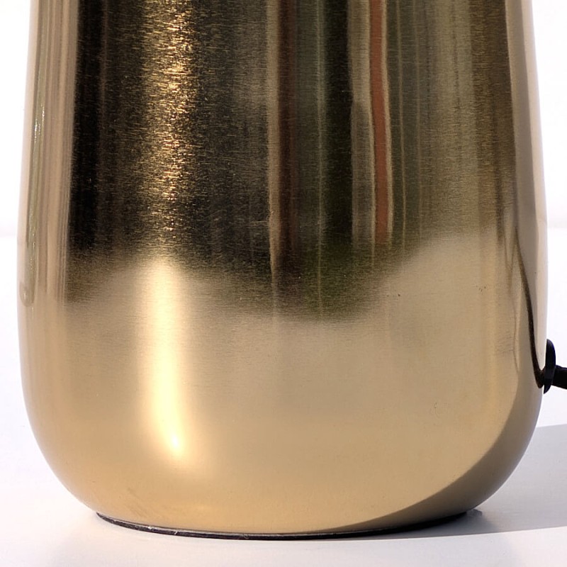 Zoom sur le pied en métal doré à la finition texturée martelée, captant la lumière avec raffinement.