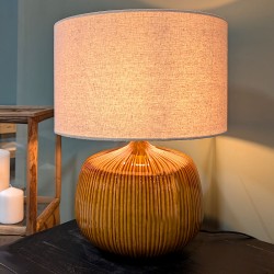 Ambiance feutrée : la lampe ocre éclairée sur un meuble en bois, diffusant une lumière douce et naturelle.