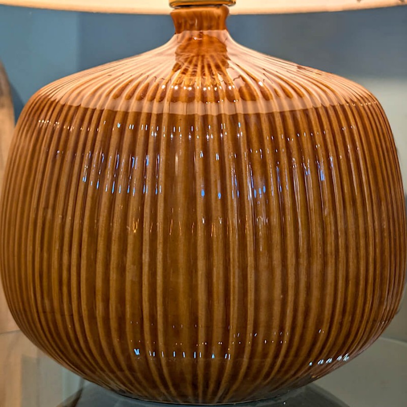 Gros plan sur le pied en grès ocre soulignant le travail artisanal des stries verticales.