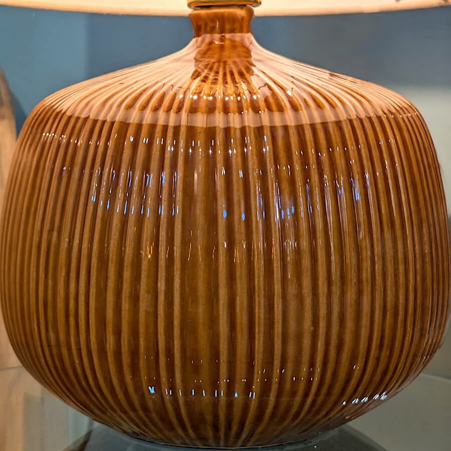 Gros plan sur le pied en grès ocre soulignant le travail artisanal des stries verticales.