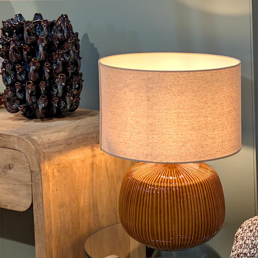 La lampe ocre intégrée dans une décoration moderne avec des objets d'art et du mobilier en bois.
