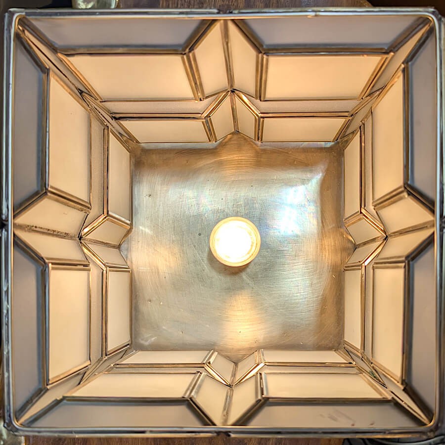 Vue plongeante de l'intérieur de la lampe allumée (ampoule E27), mettant en valeur les lignes géométriques.