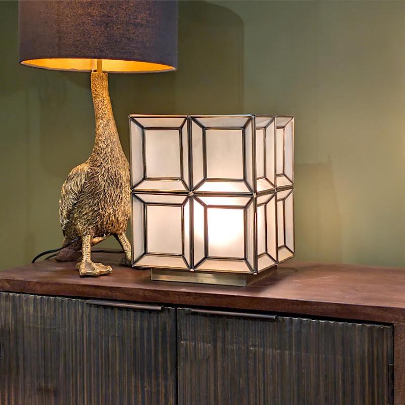 Mise en scène : la lampe cube dorée associée à une lampe autruche noire pour un contraste chic.