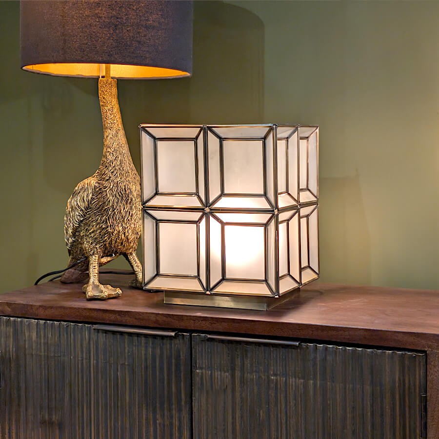 Mise en scène : la lampe cube dorée associée à une lampe autruche noire pour un contraste chic.