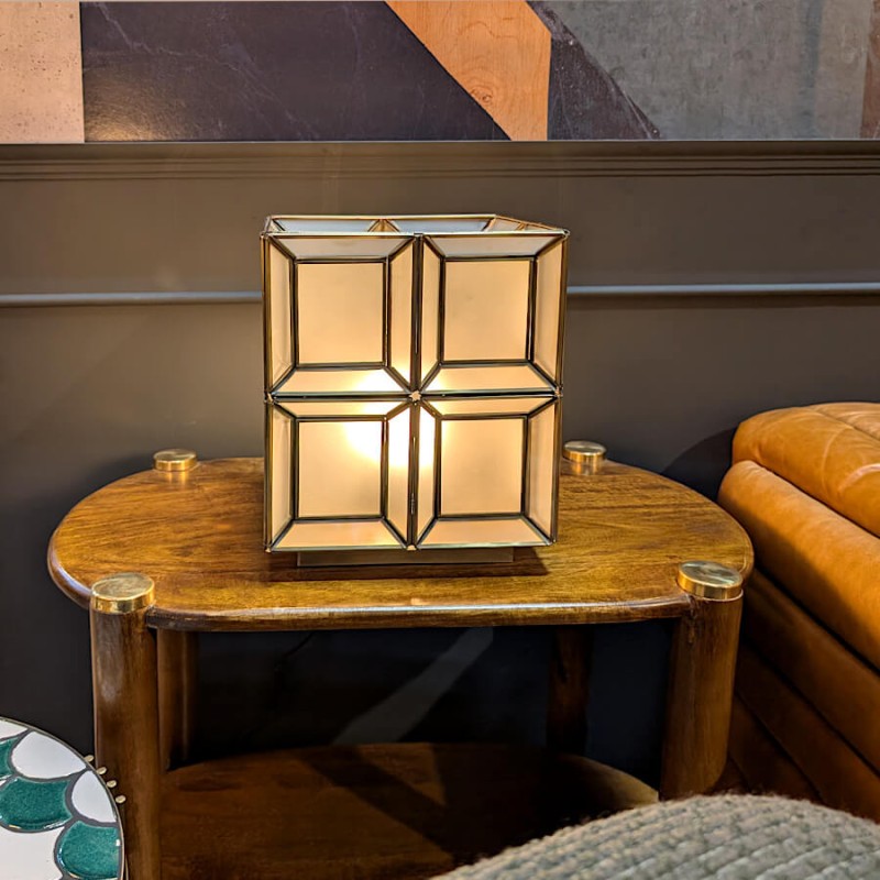 La lampe cube allumée sur un guéridon : une ambiance feutrée qui met en valeur les contrastes du métal.