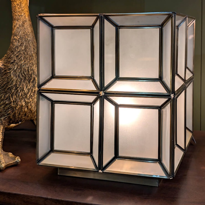 Détail de la lampe allumée soulignant le contraste entre les lignes noires des croisillons et l'éclat doré.