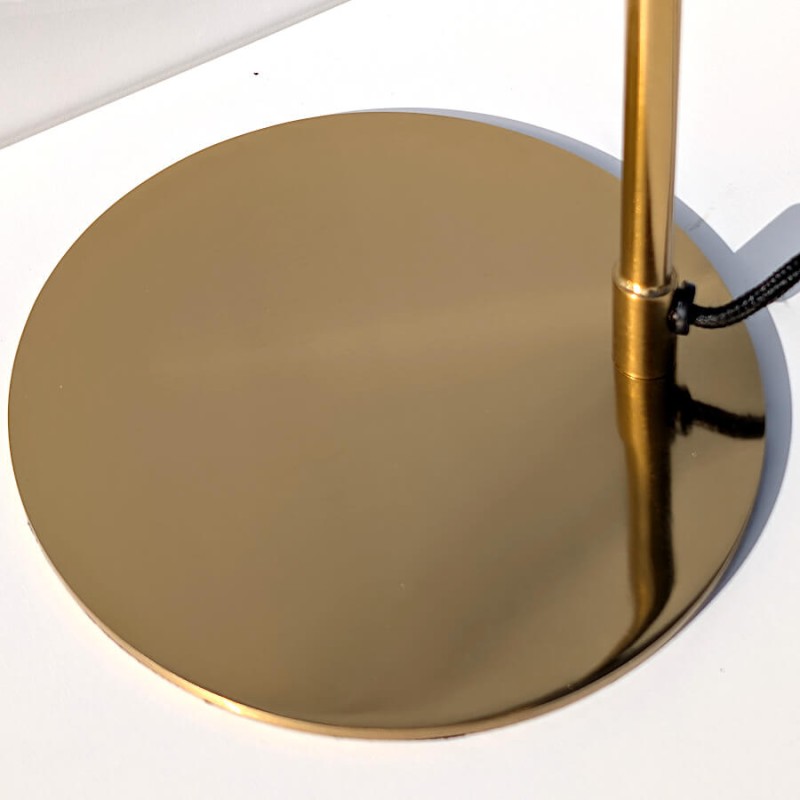 Zoom sur le socle circulaire en métal doré au fini brossé.