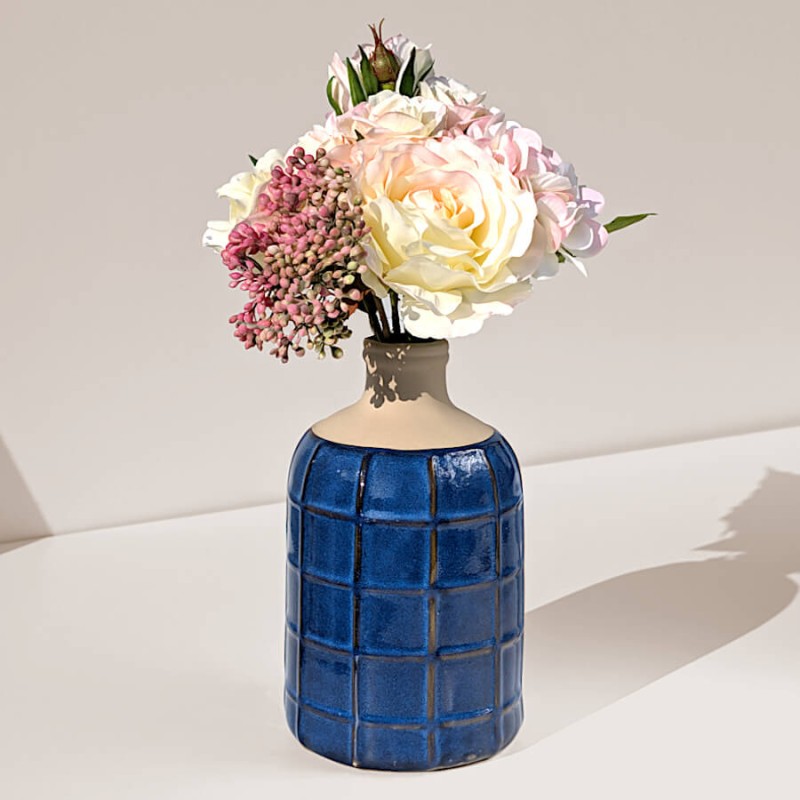 Détail d'un bouquet de pivoines et de baies roses du catalogue Deco-Delight dans le vase bleu grec.