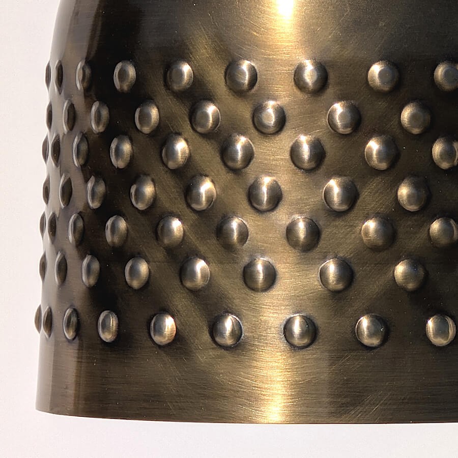 Zoom sur les détails martelés créant un motif clouté régulier.