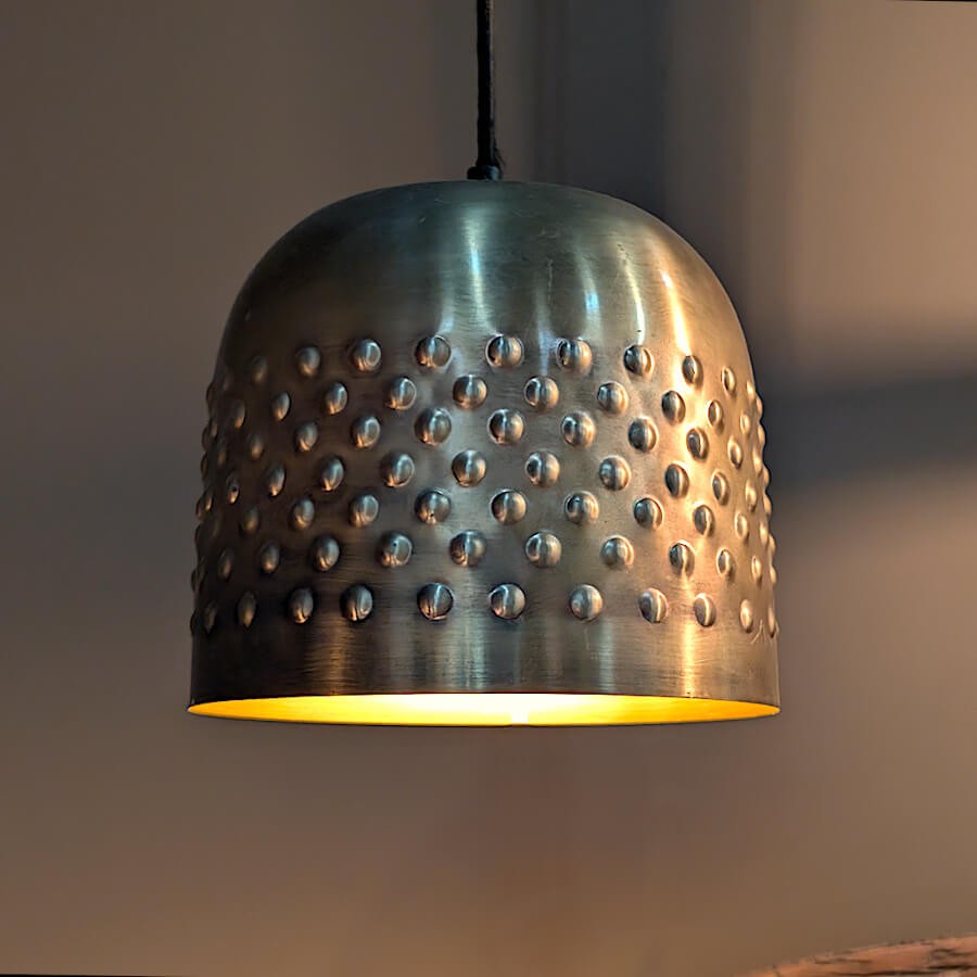 Mise en scène chic du luminaire diffusant une lumière dorée vers le bas.