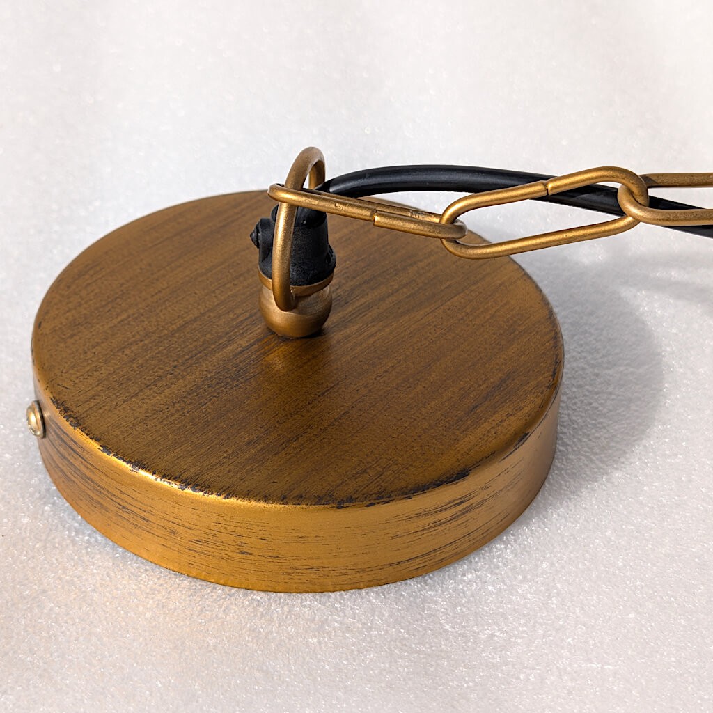 Zoom sur le pavillon de plafond circulaire en métal doré assorti.