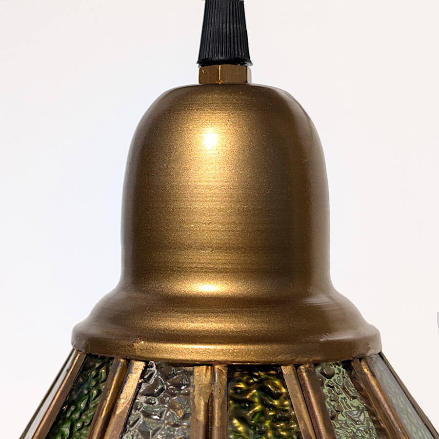 Gros plan sur la tête du luminaire en métal à la finition laiton brossé.