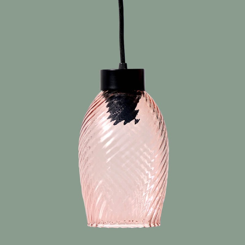 La suspension allumée sur un fond vert amande, révélant sa transparence.