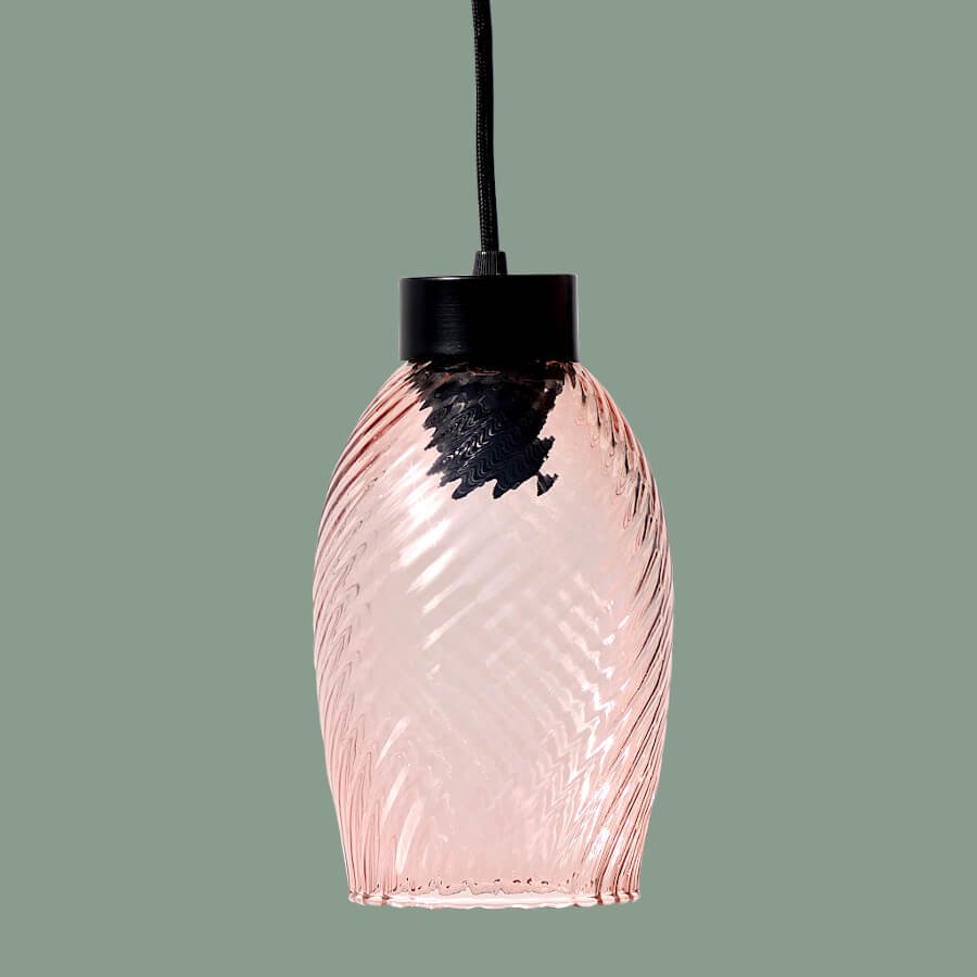 La suspension allumée sur un fond vert amande, révélant sa transparence.